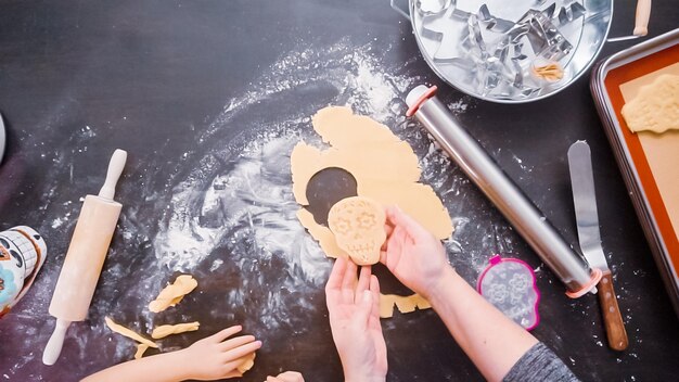 Disposizione piatta. Madre e figlia che cuociono biscotti con teschio di zucchero per la festa di Dia de los Muertos.