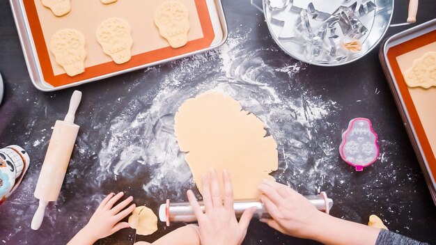 Disposizione piatta. Madre e figlia che cuociono biscotti con teschio di zucchero per la festa di Dia de los Muertos.