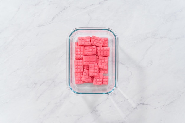 Disposizione piatta. Mini cioccolatini rosa fatti in casa in un contenitore di vetro per alimenti.
