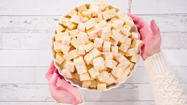 Disposizione piatta. Passo dopo passo. Caramella fondente tagliata a cubetti su un piatto da portata bianco.