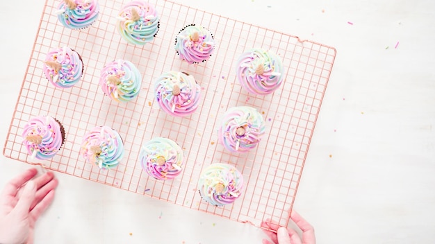 Disposizione piatta. Passo dopo passo. Cupcakes al cioccolato con glassa di unicorno con glassa di crema al burro color arcobaleno.