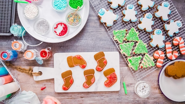 Disposizione piatta. Passo dopo passo. Decorare i biscotti di pan di zenzero e zucchero con la ghiaccia reale per Natale.