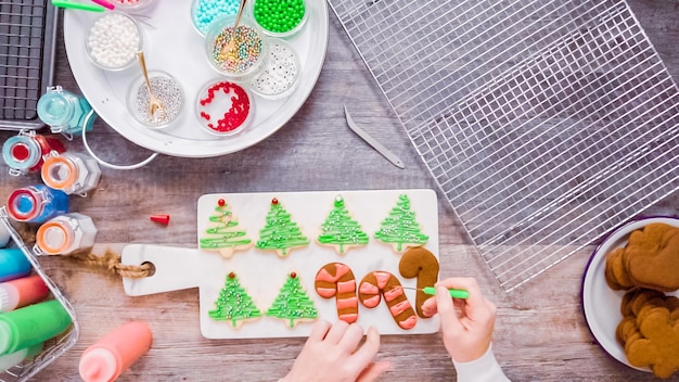 Disposizione piatta. Passo dopo passo. Decorare i biscotti di pan di zenzero e zucchero con la ghiaccia reale per Natale.