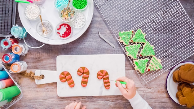 Disposizione piatta. Passo dopo passo. Decorare i biscotti di pan di zenzero e zucchero con la ghiaccia reale per Natale.