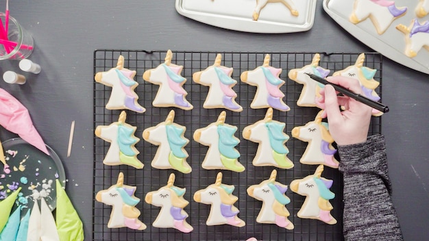 Disposizione piatta. Passo dopo passo. Dipingere il cibo glitter sopra i biscotti di zucchero di unicorno con glassa reale.