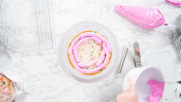 Disposizione piatta. Passo dopo passo. Glassa a strati di torta funfetti rotondi con glassa di crema al burro rosa.