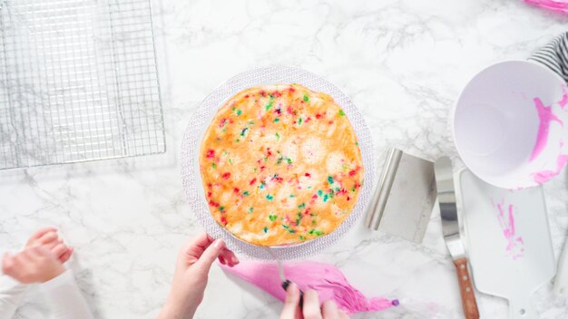 Disposizione piatta. Passo dopo passo. Glassa a strati di torta funfetti rotondi con glassa di crema al burro rosa.