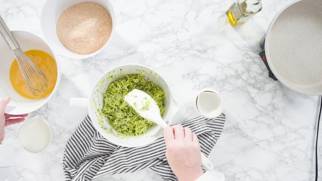 Disposizione piatta. Passo dopo passo. Mescolare gli ingredienti in una ciotola per fare le torte di zucchine.