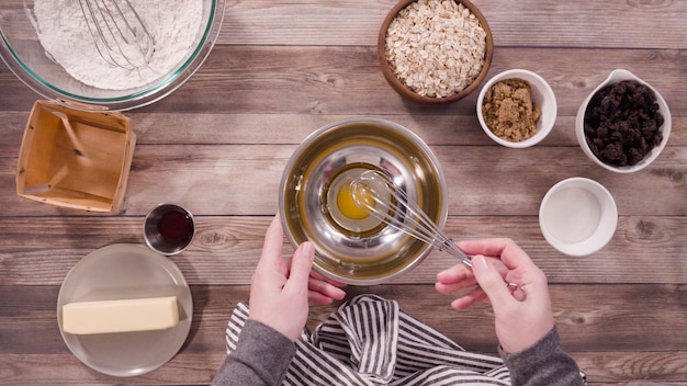 Disposizione piatta. Passo dopo passo. Mescolare gli ingredienti per cuocere i biscotti di farina d'avena in una terrina di vetro.