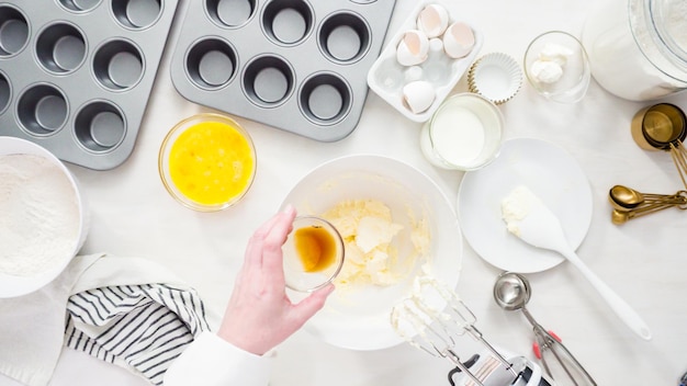 Disposizione piatta. Passo dopo passo. Mescolare la pastella per cuocere i cupcakes alla vaniglia con la glassa di crema al burro.