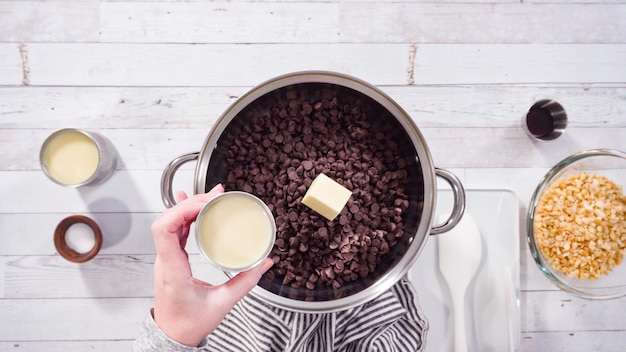 Disposizione piatta. Passo dopo passo. Sciogliere le gocce di cioccolato nella pentola per fare il fondente di noci macadamia.