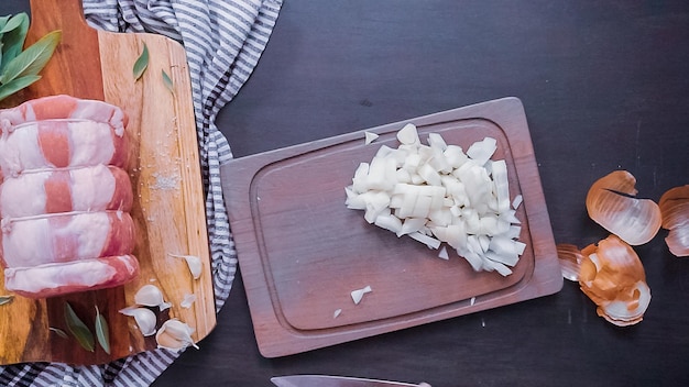 Disposizione piatta. Passo dopo passo. Tagliare a dadini la cipolla gialla su un tagliere di legno.