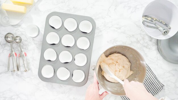 Disposizione piatta. Passo dopo passo. Versare la pastella con il misurino nello stampo per cupcake foderato con pirottini di carta.