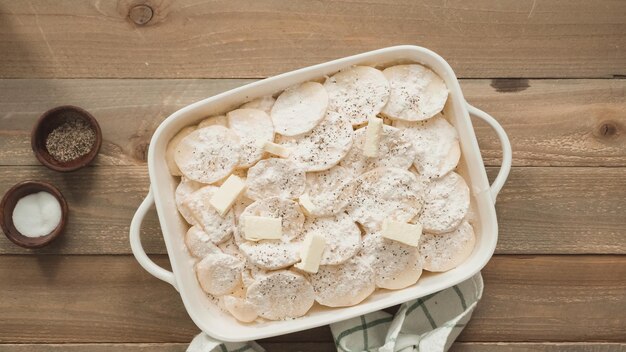 Disposizione piatta. Preparazione delle patate scaloppate in una teglia di ceramica bianca.