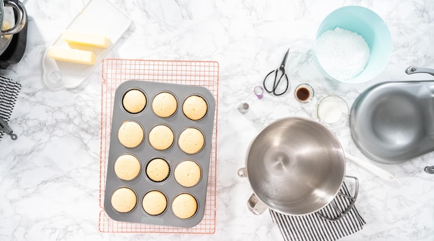 Disposizione piatta. Raffreddare i cupcakes alla vaniglia appena sfornati su uno stendino.