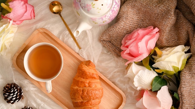 Disposizione piatta Vista dall'alto di un bellissimo tavolo da tè con fiori e decorazioni di rose croissant per tazza da tè