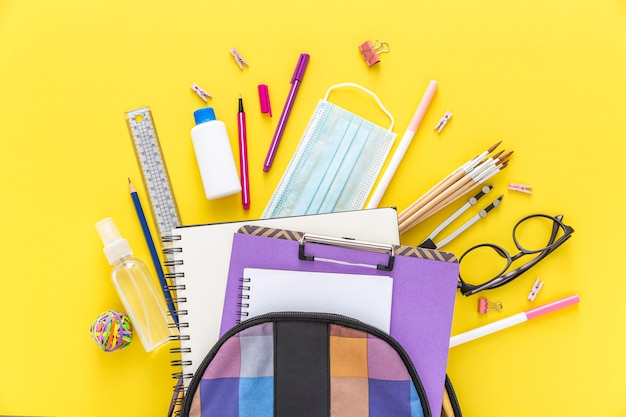 Distesa piatta di materiale scolastico con borsa per libri e occhiali