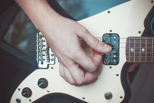 Dita che formano un accordo su una tastiera di chitarra. Mani maschili, giocando sulla chitarra. Messa a fuoco selettiva. Avvicinamento