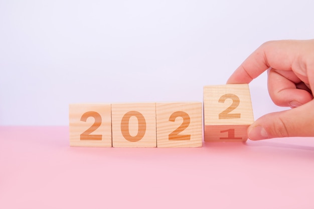 Dita che girano il blocco dal 2021 al 2022. Concetto di nuovo anno. Figure dell'anno 2022 su un blocco di legno