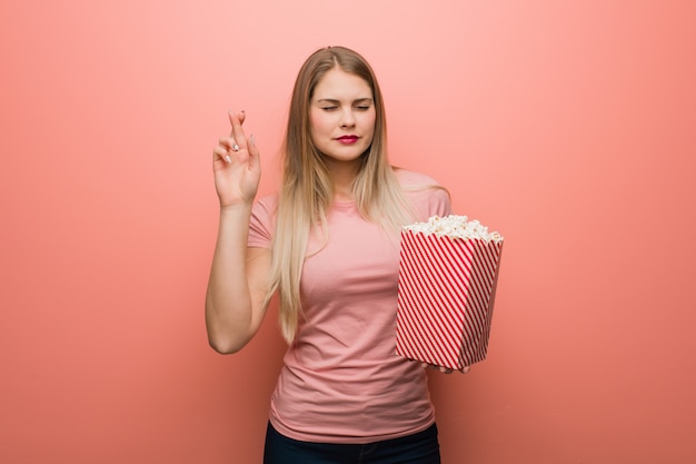 Dita dell'incrocio della ragazza abbastanza russa dei giovani per avere fortuna. Ha in mano dei popcorn.