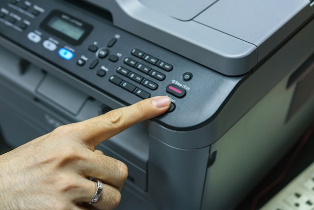 Dito che preme il pulsante di avvio del fax, apparecchiature per ufficio