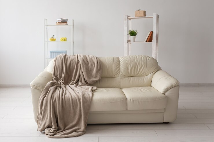 Divano beige contro la parete bianca vuota in un semplice concetto di minimalismo interno del soggiorno