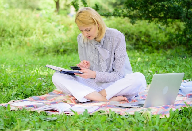 Diventa un libero professionista di successo Donna con il laptop seduto sul prato del tappeto Ragazza con il blocco note scrivi una nota Concetto di carriera freelance Guida all'inizio della carriera da freelance Donna d'affari freelance che lavora all'aperto