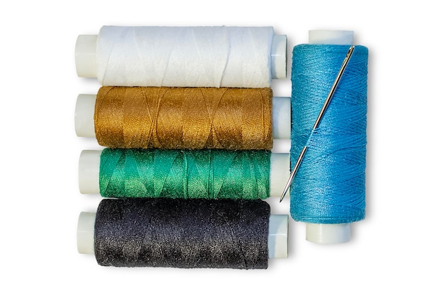 Diverse bobine di fili multicolori con un ago isolato su sfondo bianco