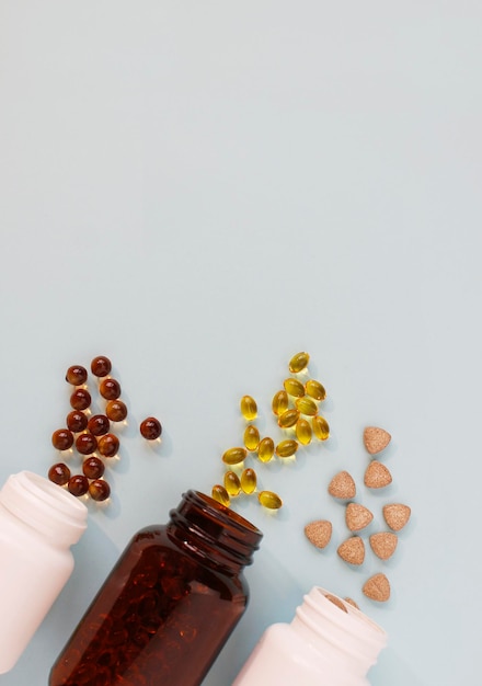 Diverse compresse, capsule, pillole sono sparse dal barattolo su uno sfondo chiaro Il concetto di salute Minimalismo