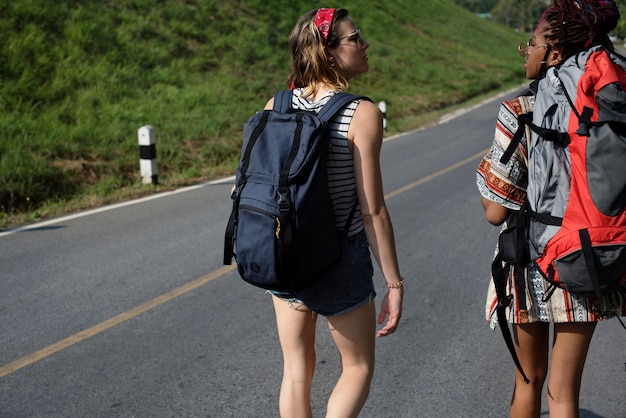 Diverse donne zaino in spalla che camminano lungo il lato della strada