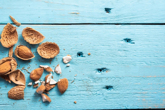 Diverse mandorle organiche aperte su uno sfondo di legno blu noci spuntino sano Prunus dulcis