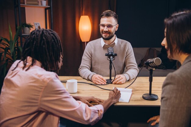 diverse podcasters recording audio content in a home studio using microphones and notepad