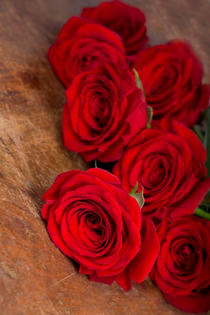 Diverse rose rosse Rose Lovely ricoperta di gocce di rossa su fondo di legno marrone