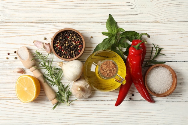 Diverse spezie ed erbe aromatiche su fondo di legno bianco, vista dall'alto