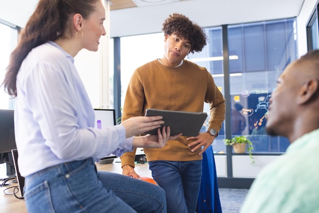 Diverse squadre che discutono su tablet in piedi in ufficio