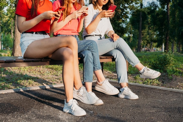 Diverse tre amiche che usano i loro telefoni all'aperto raggruppano i giovani della generazione z che usano il cellulare