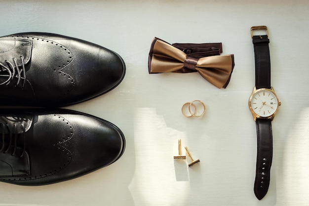 Diversi accessori da uomo come scarpe, gemelli, orologi e anelli sono sul tavolo
