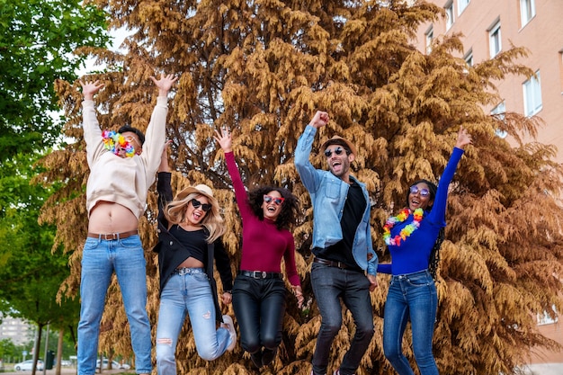 Diversi amici che celebrano il gioioso gruppo multietnico con accessori per feste godendosi il compleanno