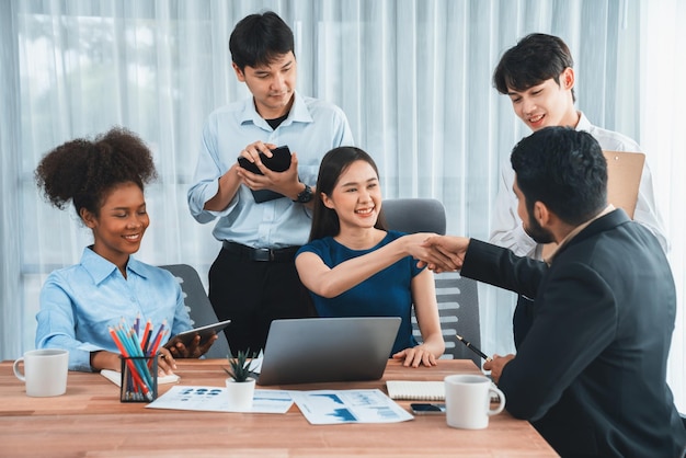 Diversi colleghi celebrano il successo con la stretta di mano e il lavoro di squadra sul posto di lavoro aziendale Team multiculturale di professionisti felici uniti nella solidarietà dalla stretta di mano in ufficio Concordia