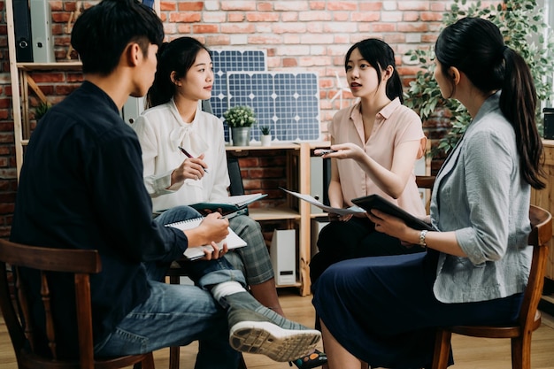 Diversi colleghi seduti in cerchio e discutono sul progetto aziendale di generazione di energia solare. lavoro di squadra dei dipendenti che parlano di opinioni e condividono idee durante la riunione in gruppo.