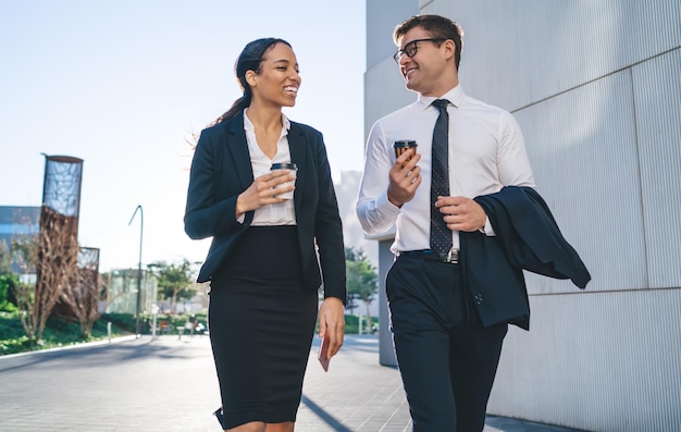 Diversi colleghi sorridenti che camminano per strada con il caffè