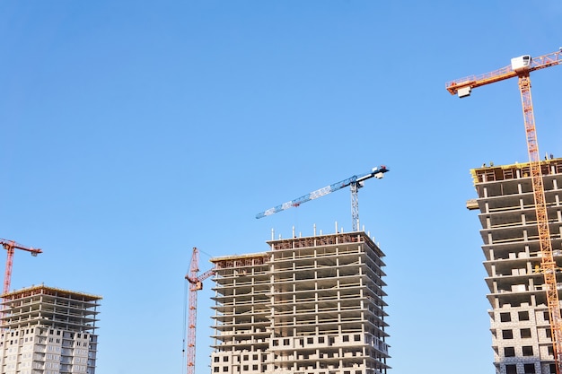 Diversi condomini multipiano in costruzione con gru a torre contro il cielo