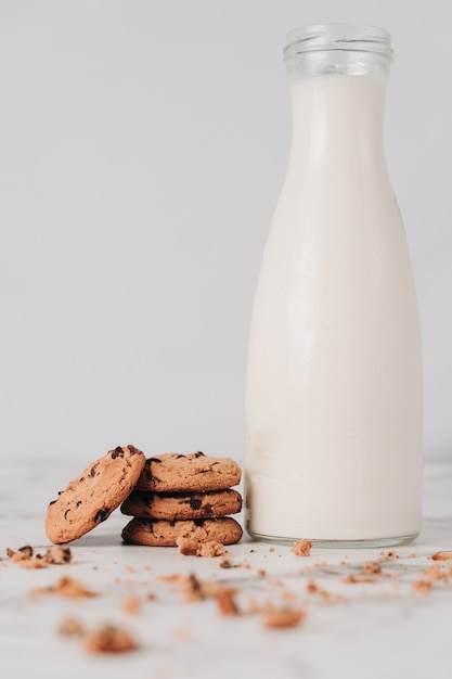 Diversi deliziosi biscotti con scaglie di cioccolato appena preparate che poggiano su una bottiglia di latte fresco