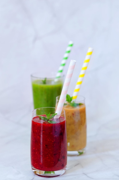 diversi frullati sani freschi in bicchieri di pesca, banana e frutti di bosco con menta. Bevande