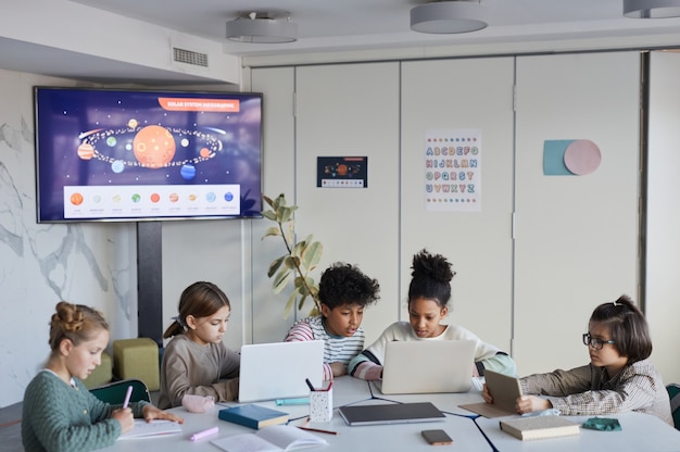 Diversi gruppi di bambini a tavola nella scuola moderna, copia spazio