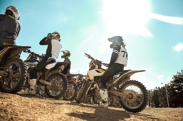 Diversi motociclisti estremi si stanno preparando per la guida fuoristrada vista posteriore contro un cielo blu Gare di moto di concetto estremo