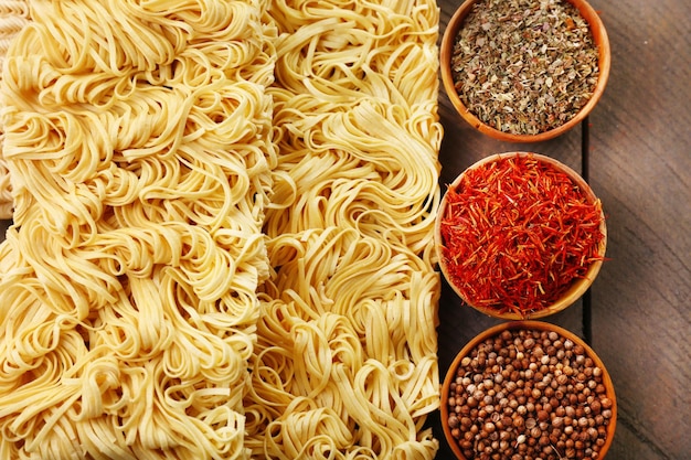 Diversi noodles istantanei secchi con spezie su sfondo di legno