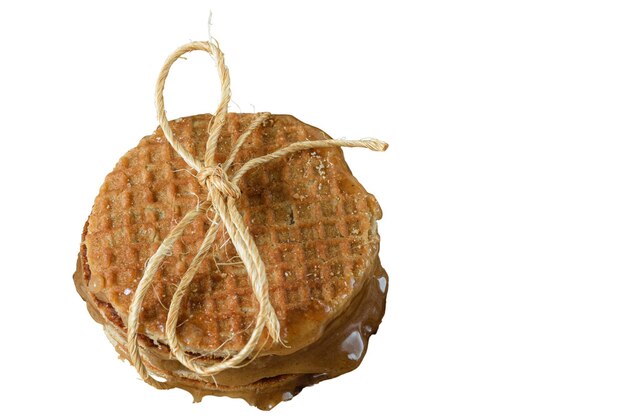 Diversi stroopwafels impilati con un arco di sisal e sciroppo zuccherato vista dall'alto sfondo bianco