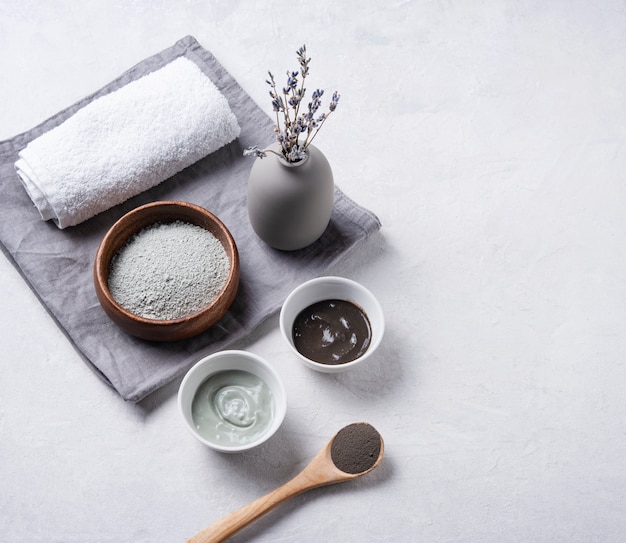 Diversi tipi di argilla cosmetica verde e grigio con lavanda su uno sfondo grigio cemento