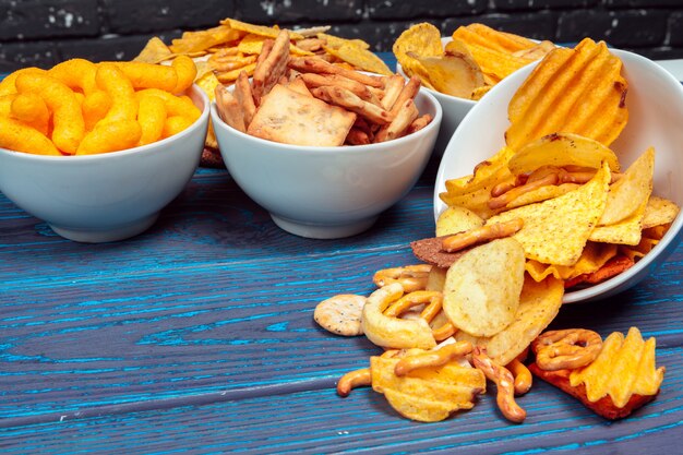 Diversi tipi di cibo spazzatura, bastoncini salati, cracker salati sul tavolo di legno